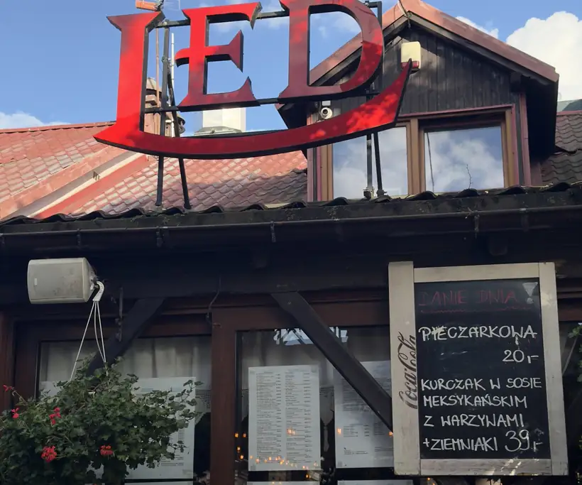 Drewniany pawilon z czerwonym napisem LED i tablicą z daniem dnia